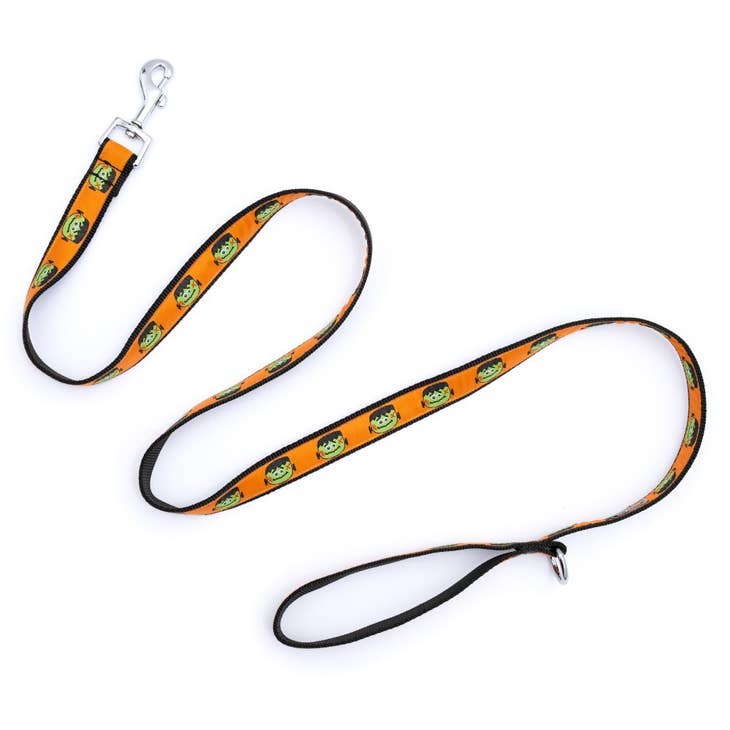 A dog leash with a black background with an orange ribbon with a Frankenstein head