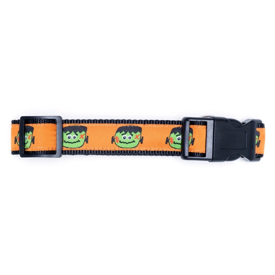 A dog collar with a black background with an orange ribbon with a Frankenstein head