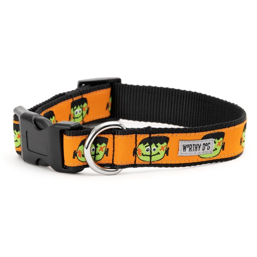 A dog collar with a black background with an orange ribbon with a Frankenstein head